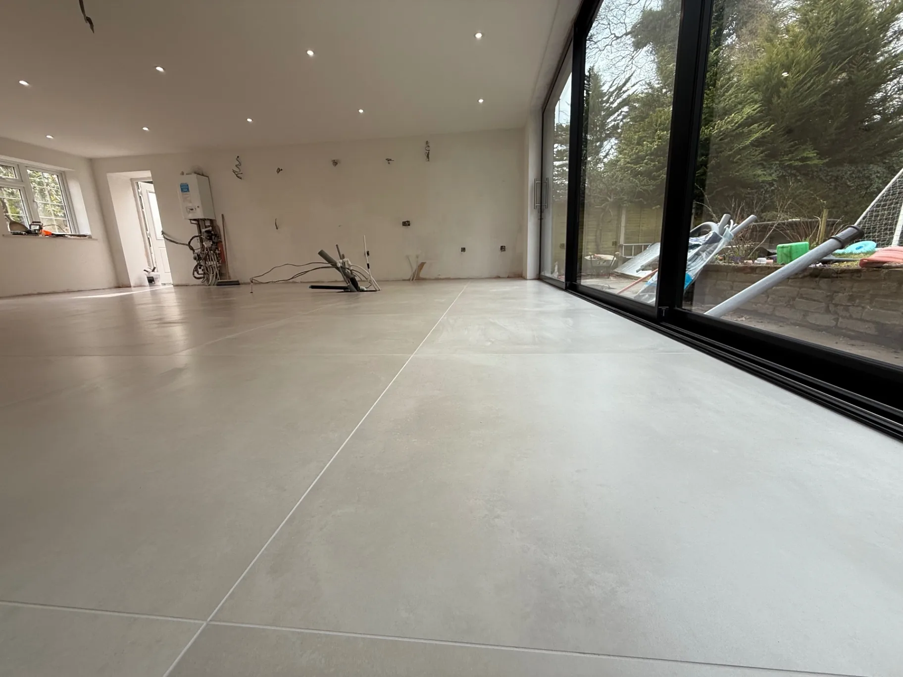 Large-format grey porcelain along the glazed wall of the extension