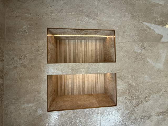 Warm stone-effect bathroom with lit niches